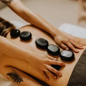 terapis meletakan batu hitam hangat di atas punggung pelanggan untuk terapi relaksasi otot di Zavra Massage.
